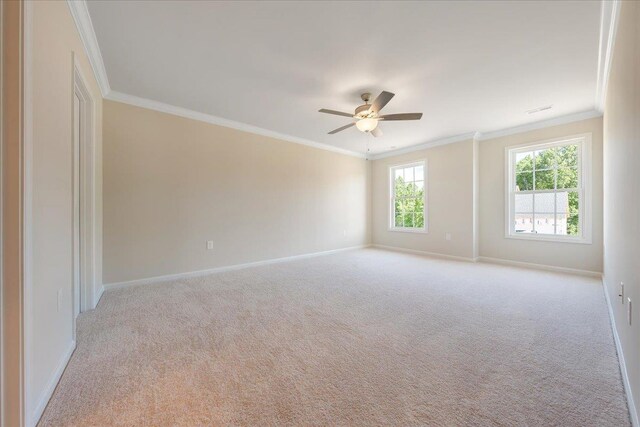 empty room with crown molding, carpet, baseboards, and ceiling fan