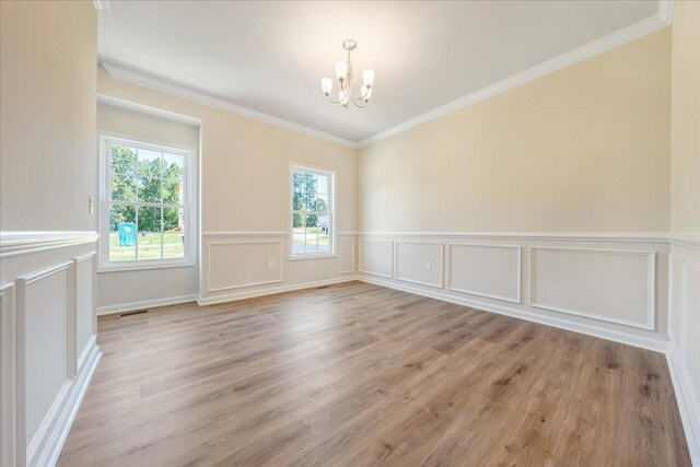 interior space with a notable chandelier, wainscoting, crown molding, and light wood-style floors