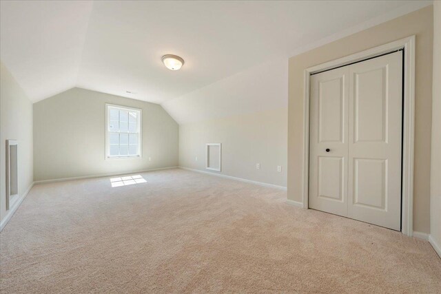 bonus room featuring vaulted ceiling, light colored carpet, and baseboards