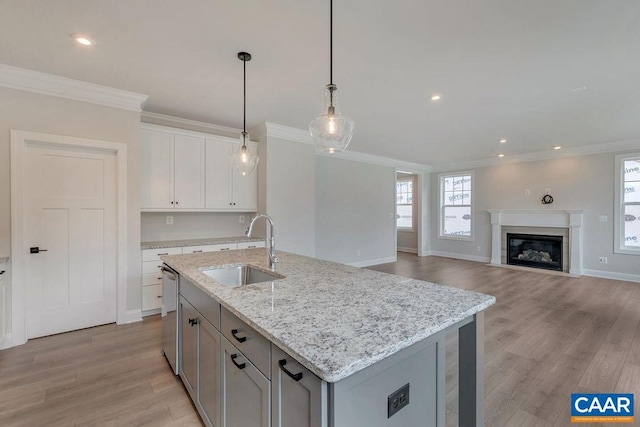 kitchen featuring light wood finished floors, dishwasher, ornamental molding, and a sink