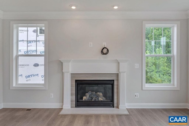 interior details with crown molding, a tile fireplace, baseboards, and wood finished floors