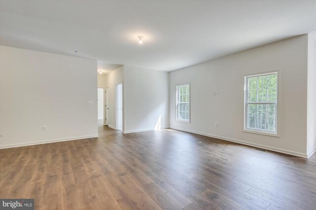 spare room with healthy amount of natural light, dark wood-style floors, and baseboards