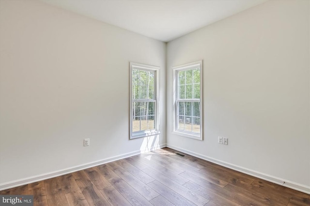 unfurnished room featuring dark wood-type flooring and baseboards
