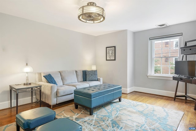 living area with wood finished floors, visible vents, and baseboards