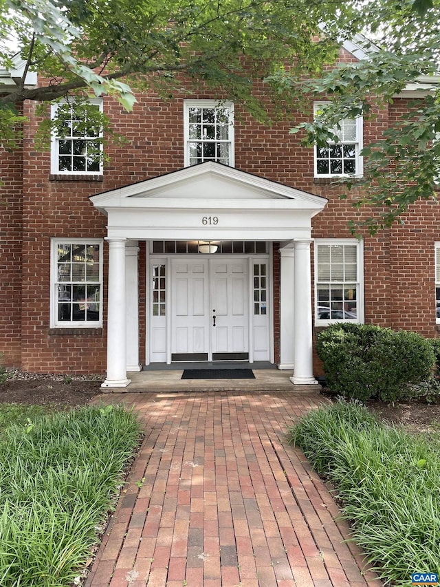 view of exterior entry featuring a porch and brick siding