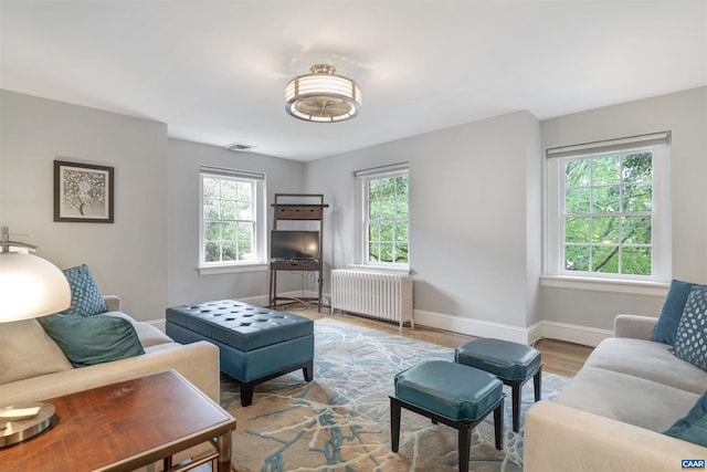living area featuring radiator, baseboards, visible vents, and wood finished floors