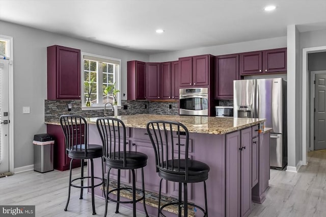 7922 Madison Plantation Way, Fredericksburg, VA 22407 - kitchen with appliances with stainless steel finishes, dark brown cabinets, light wood finished floors, decorative backsplash, and light stone counters