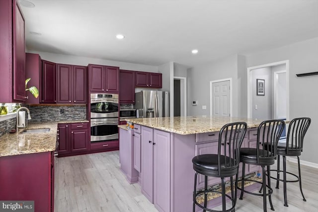 7922 Madison Plantation Way, Fredericksburg, VA 22407 - kitchen featuring appliances with stainless steel finishes, dark brown cabinets, a kitchen island, light wood-style flooring, and recessed lighting