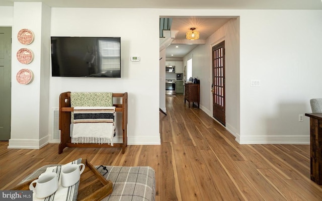 hallway featuring wood finished floors and baseboards
