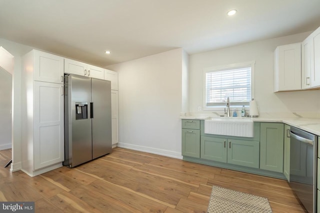 kitchen with appliances with stainless steel finishes, a sink, green cabinetry, white cabinetry, and recessed lighting