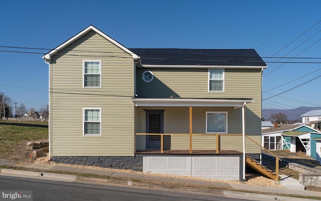 traditional-style home with roof mounted solar panels, covered porch, and stairs