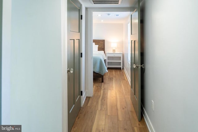 hall featuring light wood-type flooring and baseboards