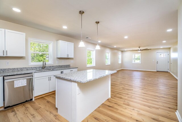 kitchen with white cabinetry, a kitchen island, light stone counters, and open floor plan