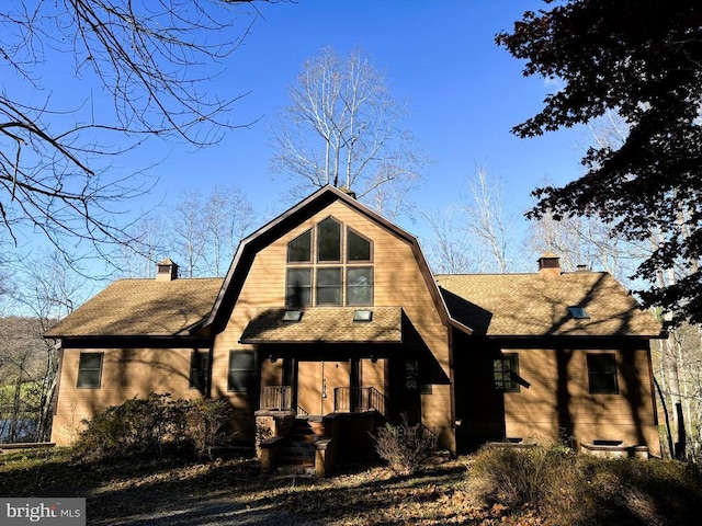  - view of front of property featuring a chimney, a gambrel roof, and a shingled roof