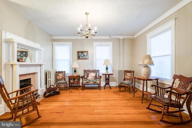 403 Long Ave, Shenandoah, VA 22849 - living area with radiator heating unit, a textured ceiling, a chandelier, light wood-type flooring, and a tile fireplace
