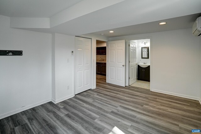 basement featuring wood finished floors, baseboards, recessed lighting, and a wall mounted air conditioner