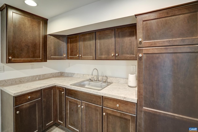 kitchen with dark brown cabinetry, light countertops, and a sink