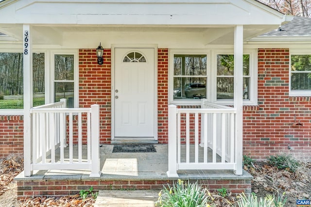 doorway to property featuring brick siding and covered porch