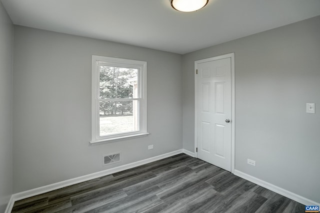 spare room with dark wood-style flooring and baseboards
