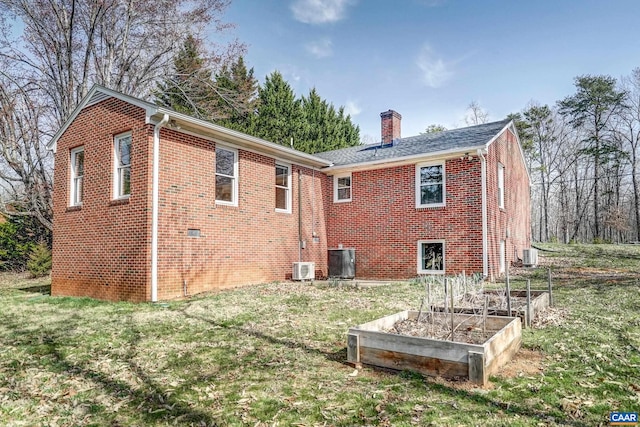 back of property featuring a chimney, a garden, and a yard