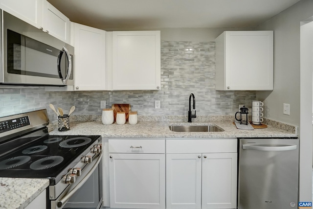 kitchen with stainless steel appliances, a sink, white cabinetry, and backsplash