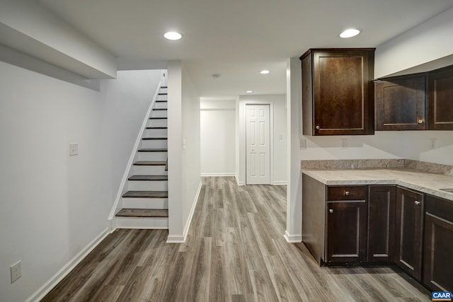 kitchen featuring wood finished floors, dark brown cabinets, light countertops, and recessed lighting