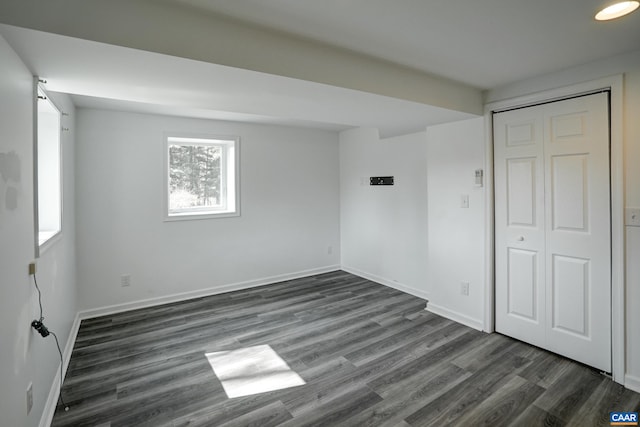 unfurnished bedroom featuring dark wood finished floors, baseboards, and a closet
