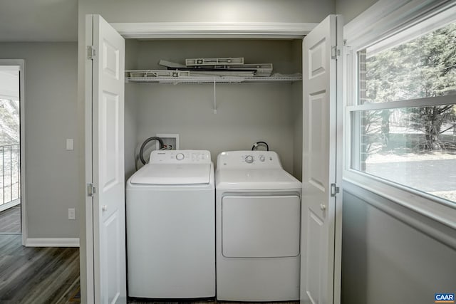clothes washing area with wood finished floors, washer and dryer, and baseboards