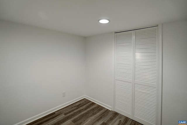 unfurnished bedroom with dark wood-style flooring, a closet, and baseboards