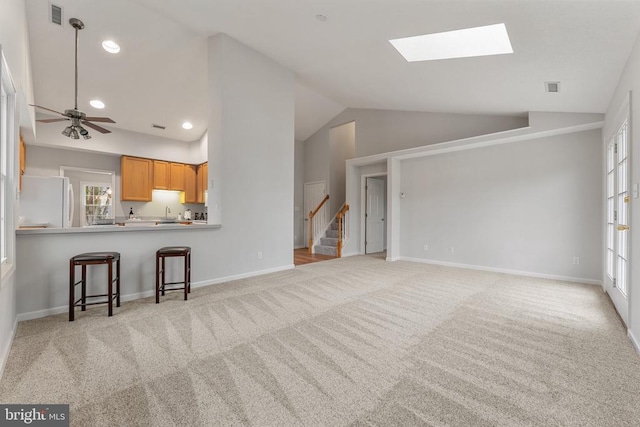 unfurnished living room with light carpet, vaulted ceiling, visible vents, and stairs