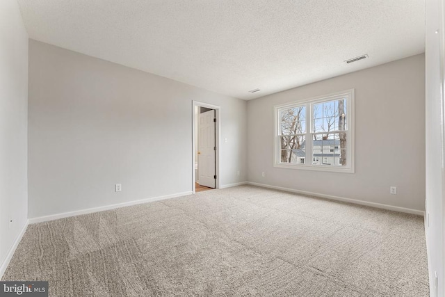 empty room with baseboards, visible vents, a textured ceiling, and carpet flooring