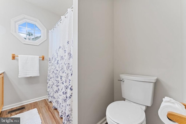 full bathroom with baseboards, visible vents, toilet, wood finished floors, and vanity