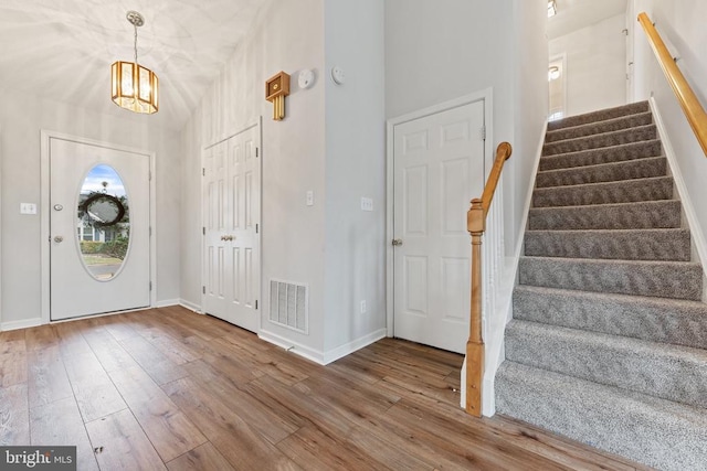 foyer featuring wood-type flooring, visible vents, stairway, and baseboards