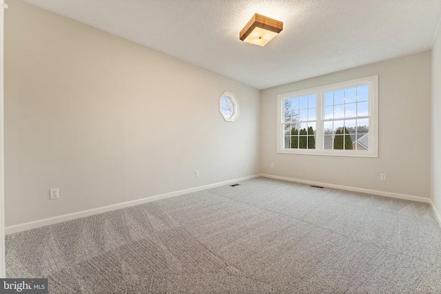 empty room featuring carpet flooring, a textured ceiling, and baseboards