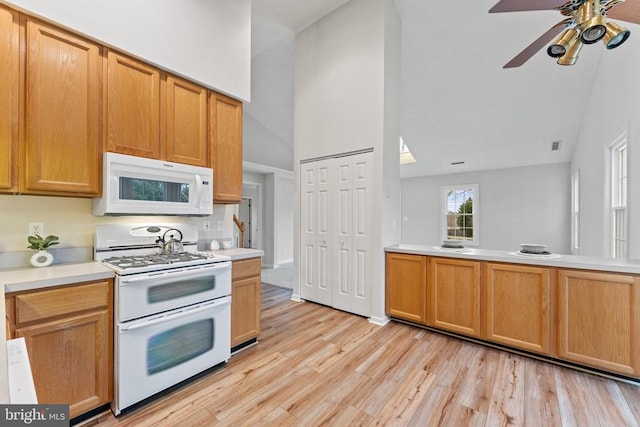 kitchen with light countertops, light wood-style floors, a ceiling fan, high vaulted ceiling, and white appliances