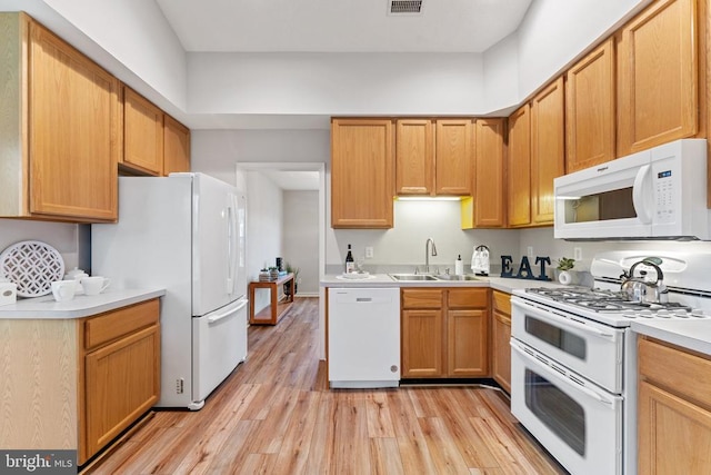 kitchen featuring light countertops, visible vents, light wood-style floors, a sink, and white appliances