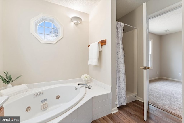 full bathroom with a whirlpool tub, curtained shower, a textured ceiling, and wood finished floors