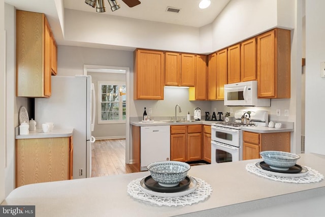 kitchen with light countertops, white appliances, visible vents, and a sink