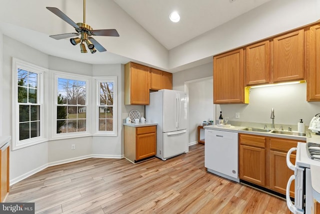 kitchen featuring white appliances, light countertops, a sink, and light wood finished floors