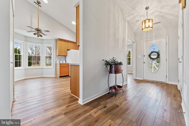 entrance foyer featuring light wood-style floors, high vaulted ceiling, and baseboards