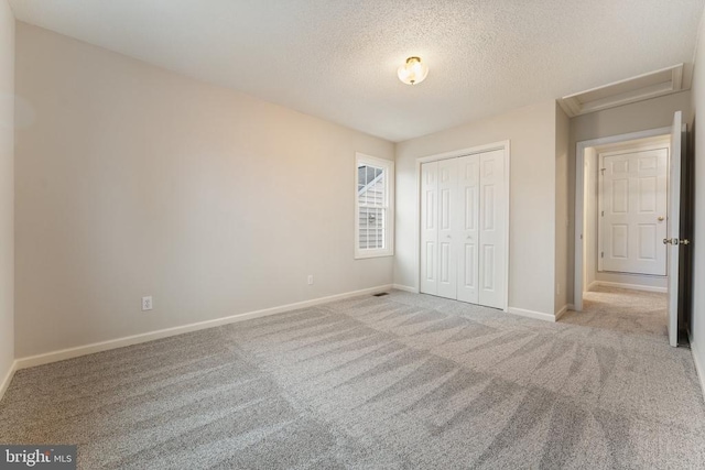 unfurnished bedroom with carpet floors, a closet, a textured ceiling, and baseboards