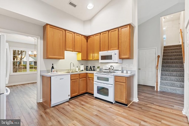 kitchen featuring white appliances, a high ceiling, a sink, visible vents, and light countertops