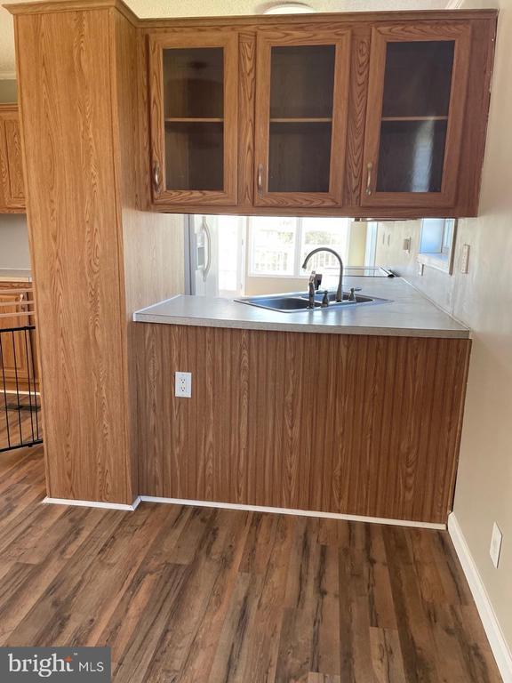 18393 Gaskins Ln, Jeffersonton, VA 22724 - kitchen with glass insert cabinets, baseboards, dark wood-style flooring, a sink, and brown cabinets