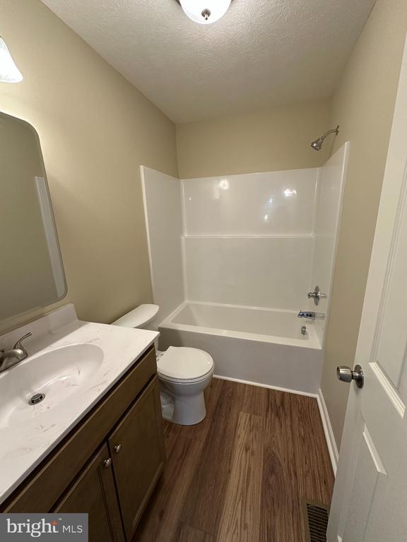 218 Honeyville Rd, Stanley, VA 22851 - bathroom with wood finished floors, a textured ceiling, bathtub / shower combination, toilet, and vanity