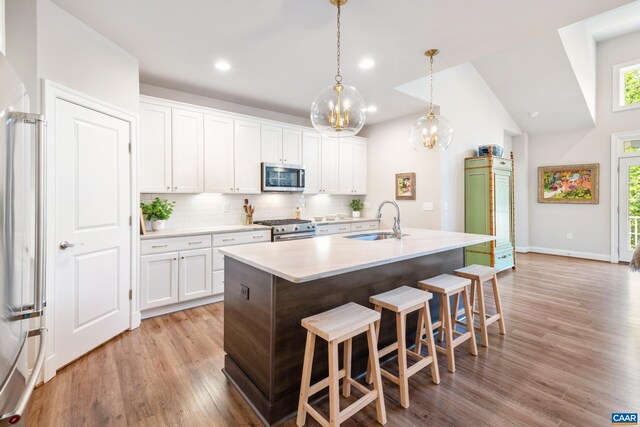 312 Avondale Ln, Crozet, VA 22932 - kitchen with stainless steel appliances, a breakfast bar, tasteful backsplash, light wood-style floors, and white cabinets