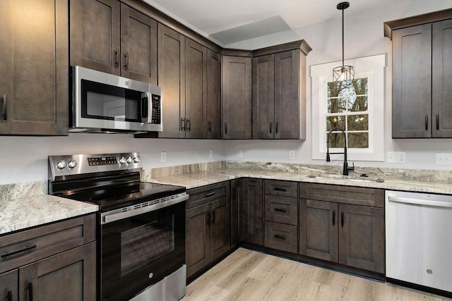 kitchen with sink, hanging light fixtures, light stone counters, dark brown cabinetry, and stainless steel appliances