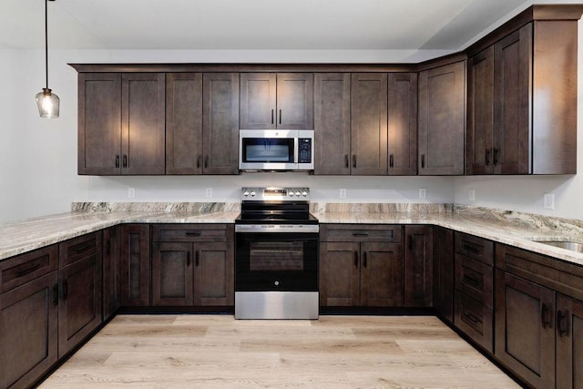 kitchen with dark brown cabinetry, light stone counters, stainless steel appliances, and light hardwood / wood-style floors