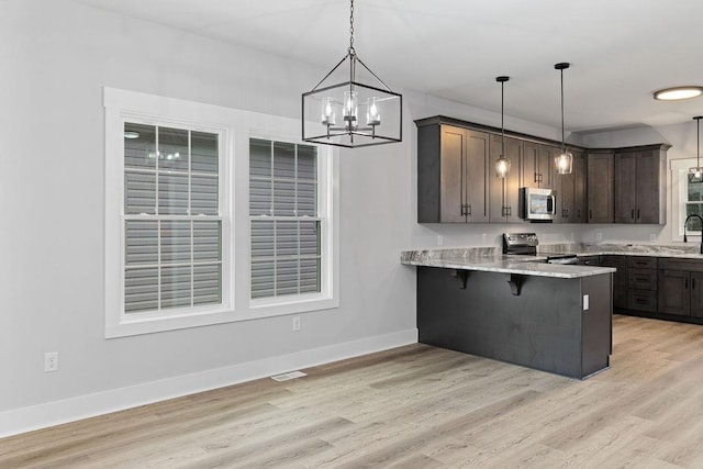 kitchen featuring pendant lighting, a breakfast bar area, kitchen peninsula, stainless steel appliances, and dark brown cabinets