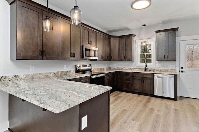 kitchen featuring dark brown cabinetry, decorative light fixtures, stainless steel appliances, and kitchen peninsula