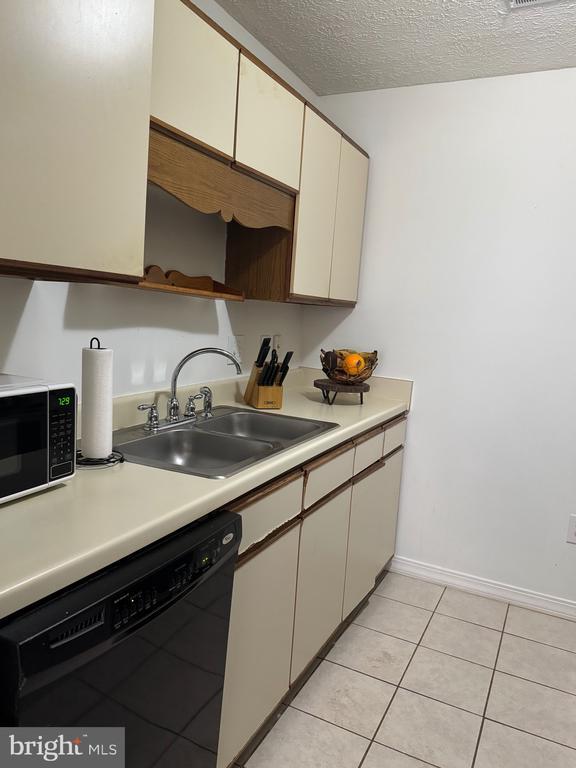 588 Meadowbrook Dr, Culpeper, VA 22701 - kitchen featuring black dishwasher, light countertops, light tile patterned flooring, a textured ceiling, and cream cabinets